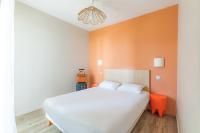 a bedroom with a white bed and an orange wall at Appart’City Confort Tours in Tours
