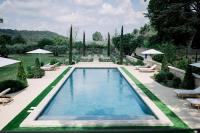 einen Pool in einem Garten mit Stühlen und Sonnenschirmen in der Unterkunft Le Domaine du Fortin in Ménerbes