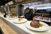 a man in a kitchen with plates of food on a counter at Crowne Plaza North Augusta, by IHG in North Augusta