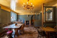 a restaurant with wooden tables and chairs and a chandelier at Kettleburgh Chequers in Kettleburgh