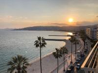 a view of a beach with palm trees and the sunset at Soleil 2023 in Antibes