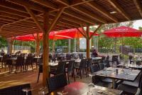 een restaurant met tafels en stoelen en rode parasols bij MOBIL HOME LMNP GUIGON in La Roque-dʼAnthéron