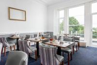 een eetkamer met tafels en stoelen en ramen bij Abbey Lawn Hotel in Torquay