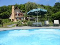 a swimming pool with an umbrella and chairs and a house at GÏTE LA DANSE DES BICHES in Ranspach
