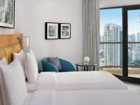 ein Hotelzimmer mit einem Bett, einem Stuhl und einem Fenster in der Unterkunft Mövenpick Hotel Jumeirah Beach in Dubai