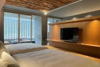 a bedroom with a large bed and a flat screen tv at Onsen Papawaqa in Tai&#39;an
