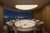 a dining room with a long table and chairs and a window at lebua at State Tower in Bangkok