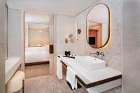 a bathroom with a sink and a mirror and a bed at Sheraton Abu Dhabi Hotel & Resort in Abu Dhabi