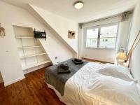 a bedroom with a white bed and a staircase at Maison de pêcheur - À 200m de la plage in Ploemeur