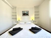a large white bed with two black pillows on it at Maison de pêcheur - À 200m de la plage in Ploemeur