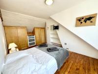 a bedroom with a white bed and a staircase at Maison de pêcheur - À 200m de la plage in Ploemeur