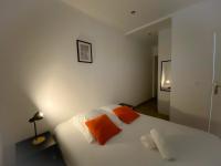 a bedroom with a white bed with two orange pillows at Les Dunes 1 in Sangatte