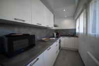 a kitchen with white cabinets and a black microwave at Les cerisiers un petit coin de paradis pour deux proche du lac! in Sévrier