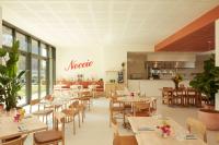 Un restaurante con mesas y sillas y una cocina. en OKKO Hotels Paris Rosa Parks, en París