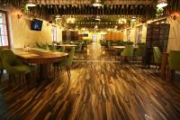 ein Esszimmer mit Holztischen und grünen Stühlen in der Unterkunft Conacul Radacinilor in Petroşani