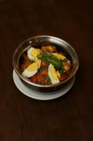 una ciotola di metallo con del cibo su un piatto su un tavolo di Magnum Inn a Lahore