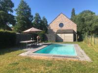 a swimming pool in a yard with a table and an umbrella at landelijke villa met zwembad en gezellige openhaard in Zemst