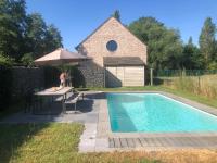 a swimming pool with a table and an umbrella at landelijke villa met zwembad en gezellige openhaard in Zemst