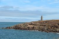 a lighthouse on a rocky island in the ocean at Sur le chemin de la plage in Cherbourg en Cotentin