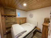 a small bed in a room with a wooden ceiling at La cabane de dany in La Bresse