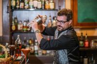a man standing behind a bar mixing a drink at 1905 Basin Park Hotel in Eureka Springs