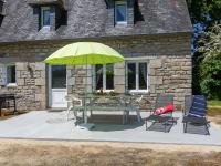 a table with chairs and a green umbrella in front of a building at Holiday Home Blaue Hortensie - SZN100 by Interhome in Sizun