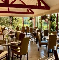 Un restaurante con mesas, sillas y ventanas. en Logis Hostellerie la Chaumière, en Arsonval