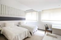 a white room with two beds and a chair at Dandy Hotel - Tianmu Branch in Taipei