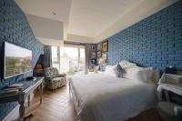 a bedroom with a white bed and a blue brick wall at Kenting 4 Sisters Villa in Eluan