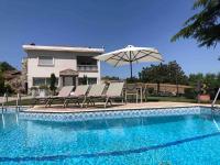 a pool with chairs and an umbrella next to a house at Villa Casa Chrissy in Plagiárion