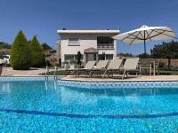 a swimming pool with chairs and an umbrella and a house at Villa Casa Chrissy in Plagiárion