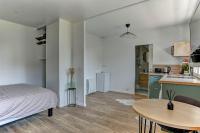 a bedroom with a bed and a table and a kitchen at Le Normand- Bois d&#39;arcy in Bois-dʼArcy