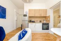a kitchen with white cabinets and a white refrigerator at 2 pièces tout confort, déco moderne, wifi fibre in Grenoble