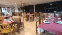 a dining room with red tables and wooden chairs at Pension Parrilla Casa Vicente in Tineo