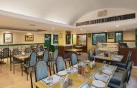 Un restaurante con mesas y sillas en una sala. en The Cama - A Sabarmati Riverfront Hotel, en Ahmedabad