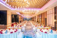 Un largo salón de banquetes con mesas y sillas blancas. en Grand Hyams Hotel - Quy Nhon Beach, en Quy Nhon