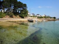a boat sitting in the water next to a beach at 30 m des Plages - Port du Magouër - 6 invités in Plouhinec