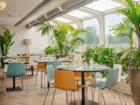 Un restaurante con mesas, sillas y plantas. en Novotel Paris Centre Tour Eiffel, en París