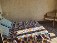 a bedroom with a quilt on a bed with a chair at Manoir en Crau in Arles