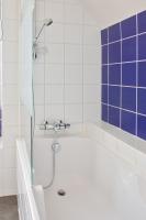 a bathroom with a tub and a shower with blue tiles at Escapade au calme tout pres de la plage in Penmarch