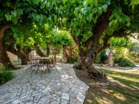 a stone walkway with a table and chairs under a tree at Holiday Home Le Mas d&#39;Adélaïs by Interhome in Baron