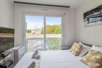 a bedroom with a white bed with a large window at Appartement Tasdon - Welkeys in La Rochelle