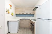 a kitchen with a white refrigerator and wooden cabinets at Appartement familial avec jardin ensoleillé dans la cité des Potiers in Vallauris
