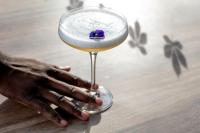 uma mão segurando um copo com uma flor roxa dentro. em Bedford Hotel em Londres