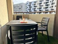 a table with a bottle and two chairs on a balcony at BARCABEACH front de mer avec terrasse et parking in Le Barcarès