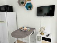 a room with a table and a tv and a refrigerator at BARCABEACH front de mer avec terrasse et parking in Le Barcarès