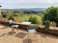 a table and chairs on a patio with a stone wall at Mazille Les Trois Monts in Mazille
