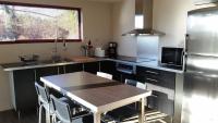 a kitchen with a table and a stainless steel refrigerator at Au milieu des vignes piscine chauffée clim dans maison vigneronne in Mondragon