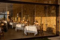 a restaurant with white tables and chairs and a stone wall at Castello di Velona Resort, Thermal SPA & Winery in Montalcino