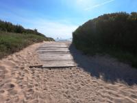 a wooden path on a beach near the water at Presqu&#39;ile de Giens - Hameau de la Pinede in Hyères
